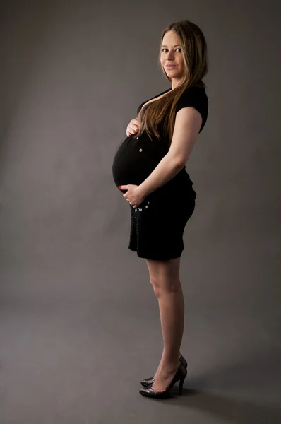 Junge schöne schwangere Frau im schwarzen Kleid. — Stockfoto