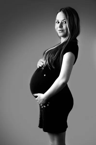 Jonge mooie zwangere vrouw in zwarte jurk. — Stockfoto
