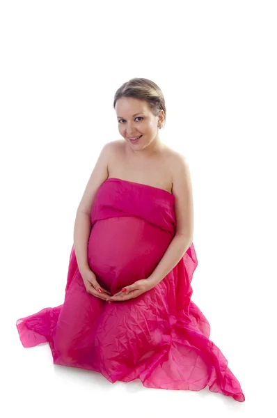 Krásná těhotná mladá žena v růžovou foukání šaty — Stock fotografie