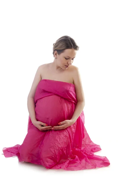 Hermosa mujer joven embarazada en vestido de soplado rosa — Foto de Stock