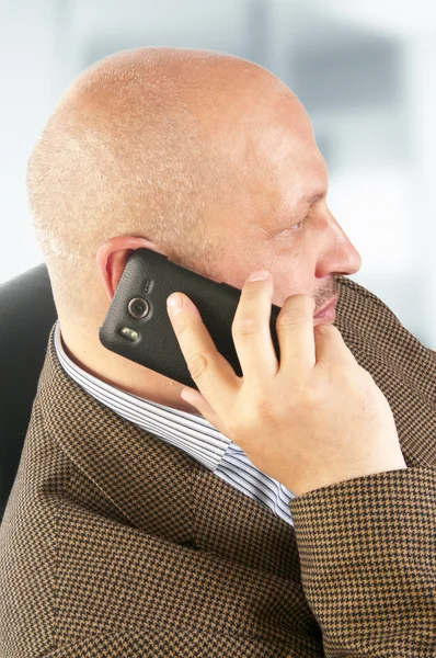 Biznesmen rozmawiający przez telefon siedzący na krześle. — Zdjęcie stockowe