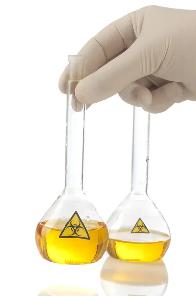 Hand hält Medizingeröhrchen aus Glas mit gelber Flüssigkeit und Symbol Biohazard. — Stockfoto