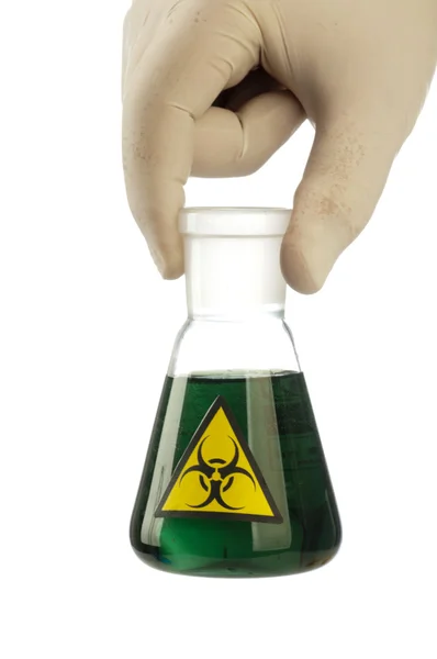 Mão segura tubo de vidro com fluido verde e símbolo de risco biológico . — Fotografia de Stock