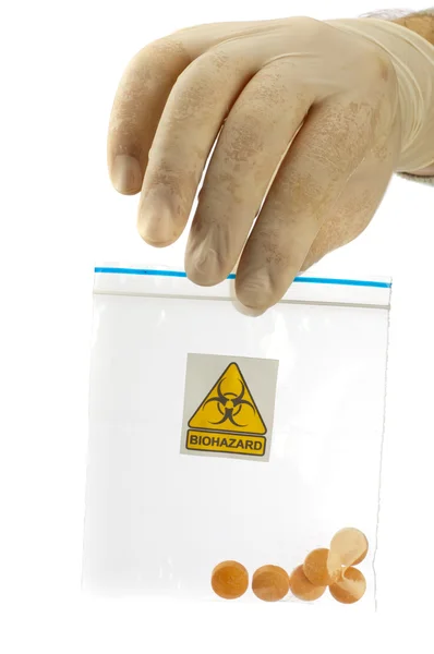 Mão segura pacote com medicamentos e símbolo de risco biológico . — Fotografia de Stock