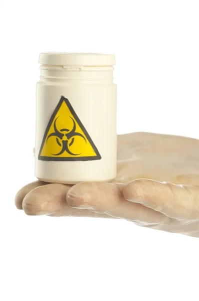 Hand houdt pot geneesmiddel met symbool biohazard. — Stockfoto