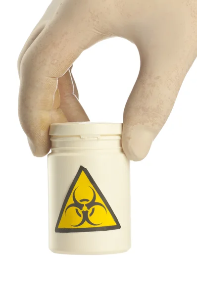 Ruka drží sklenici léku s symbolem biohazard. — Stock fotografie