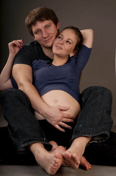 Casal adulto jovem abraçar, com mulheres pragnantes — Fotografia de Stock