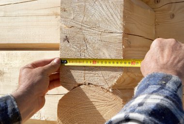 Carpenter measures wooden logs clipart