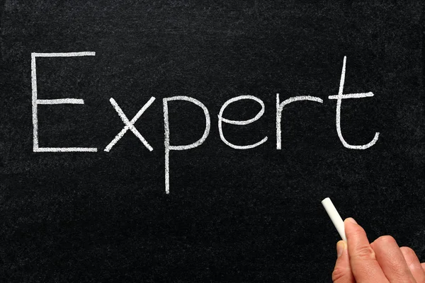 Writing expert with white chalk on a blackboard. Royalty Free Stock Photos
