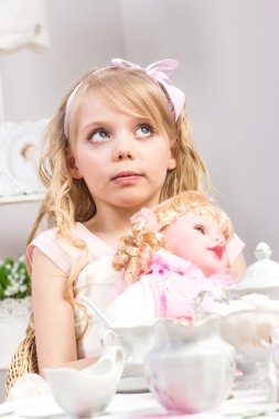 A beautiful little girl having a tea party with her baby doll clipart