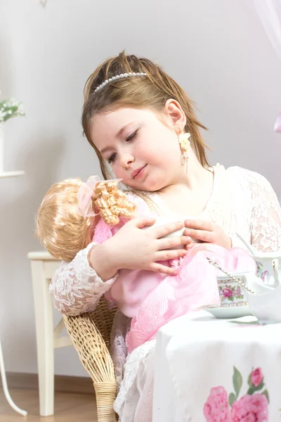 En vacker liten flicka med ett te-party med hennes baby doll — Stockfoto