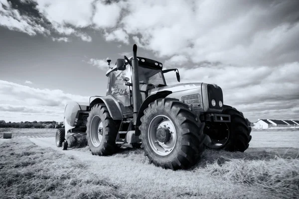 Traktor sammelt Heuhaufen auf dem Feld, Schwenktechnik — Stockfoto