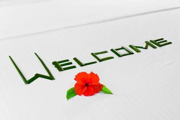 Ordet Välkommen och blomma på säng i hotel — Stockfoto