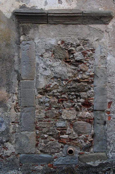 Старе вікно в сірій кам'яній стіні заблоковане цеглою і камінням — стокове фото