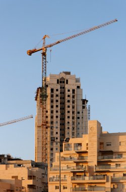 Lifting crane and building under construction at sunset clipart