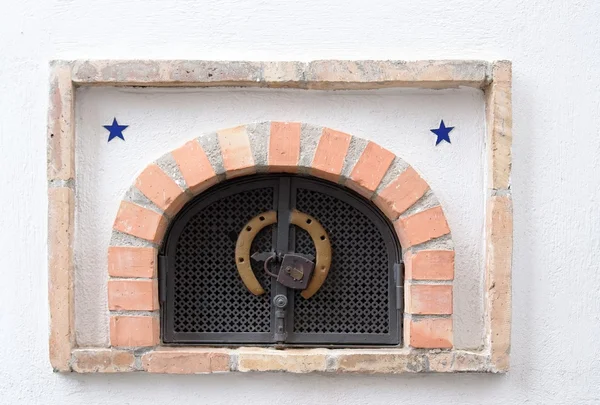 Small ventilation window with grate, padlock and horseshoe — Stock Photo, Image