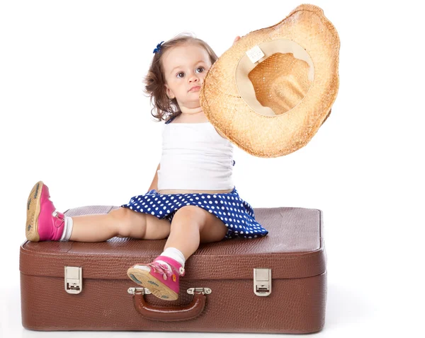 Ein Mädchen sitzt auf einem Koffer. — Stockfoto