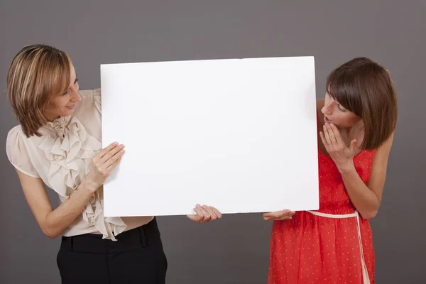 Dos mujeres sorprendidas con pancarta blanca — Foto de Stock