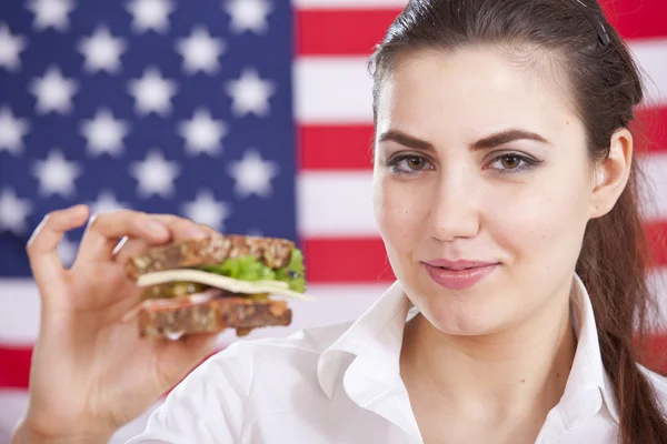 Женщина с бутербродом над американским флагом — стоковое фото