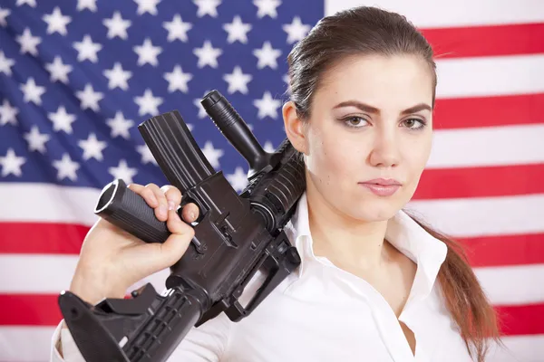 Frau mit Maschinengewehr über amerikanischer Flagge — Stockfoto