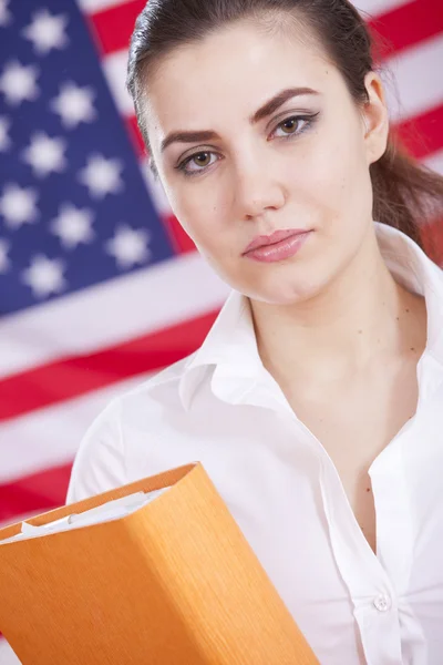 Женщина с папкой над американским флагом — стоковое фото