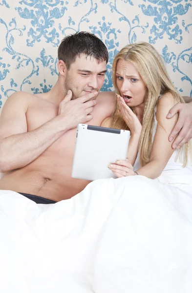 Пара з планшетним комп'ютером у ліжку — стокове фото