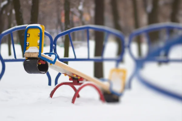 Качели детская площадка в снегу — стоковое фото