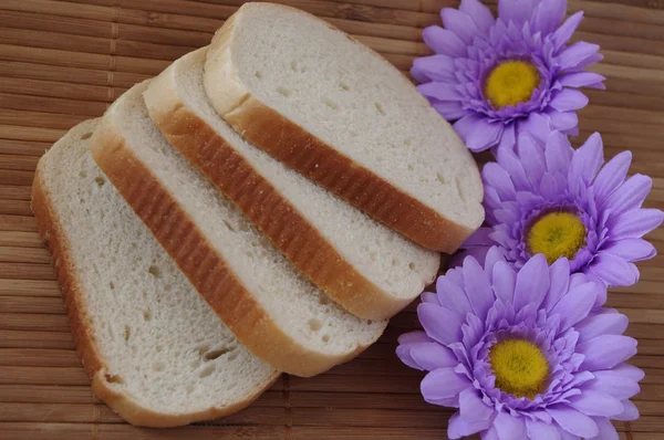 White bread and flowers on bamboo napkin — Stock Photo, Image