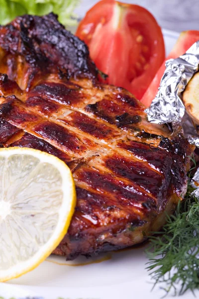 Мясо жареной свинины на тарелке с зеленым салатом — стоковое фото