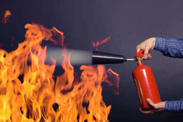 Hombre con extintor luchando contra un fuego Fotos De Stock