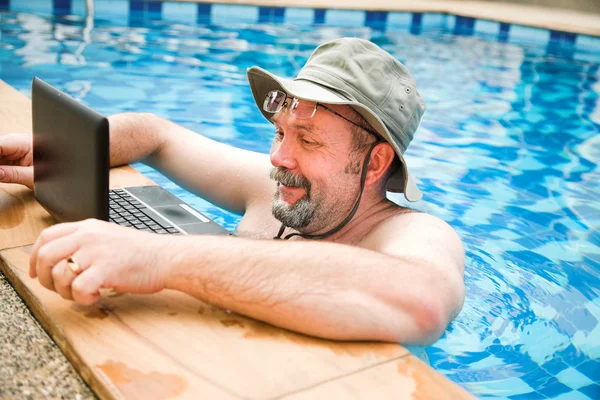 Человек в бассейне работает с ноутбуком — стоковое фото
