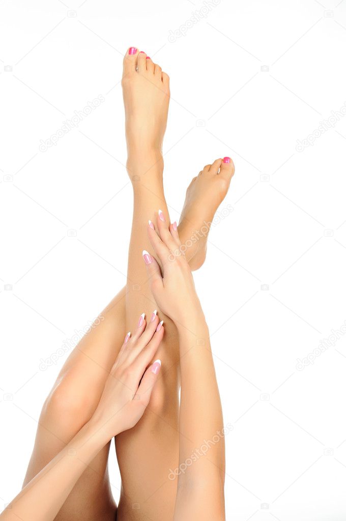 Slender naked female legs being massaged isolated on white