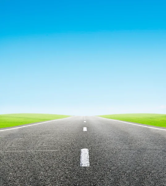 Groen veld en weg over blauwe hemel — Stockfoto