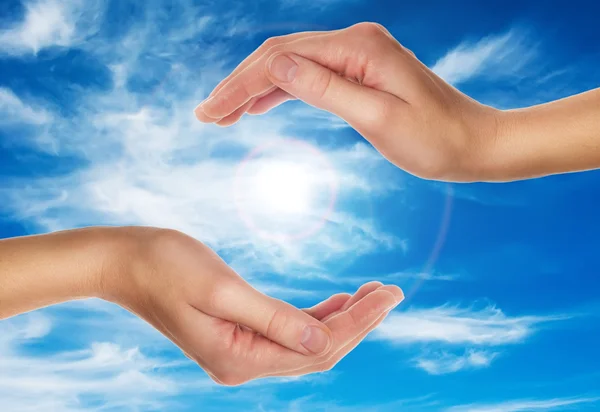 Vrouwelijke handen over blauwe hemel met wolken — Stockfoto