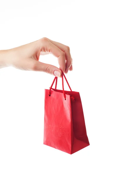 Mano femenina sosteniendo bolsa de regalo roja con presente con sus dedos  - — Foto de Stock