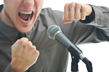 Businessman screaming in microphone with his fist rased up isola clipart