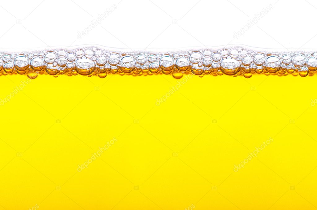 Close up shot of yellow beer with foam and bubbles on white back