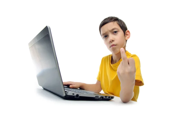 Сердитий агресивний хлопчик у жовтій футболці з ноутбуком, що показує середину ліжка — стокове фото