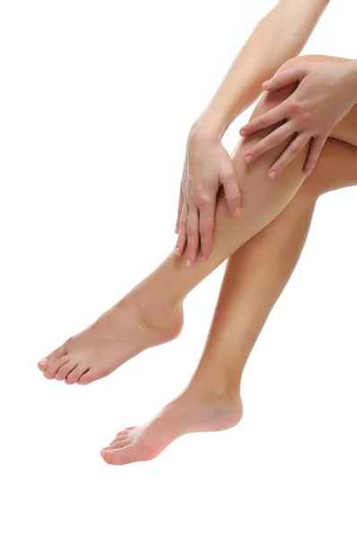 Bliska smukłe nagie nogi, które są masowane na białym tle — Zdjęcie stockowe