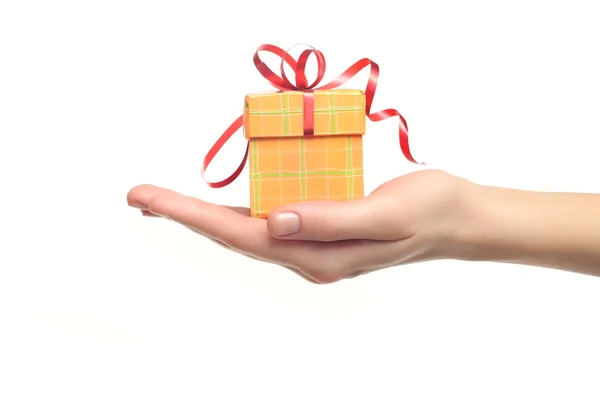Female hand holding red and yellow gift box with a bow isolated — Stock Photo, Image