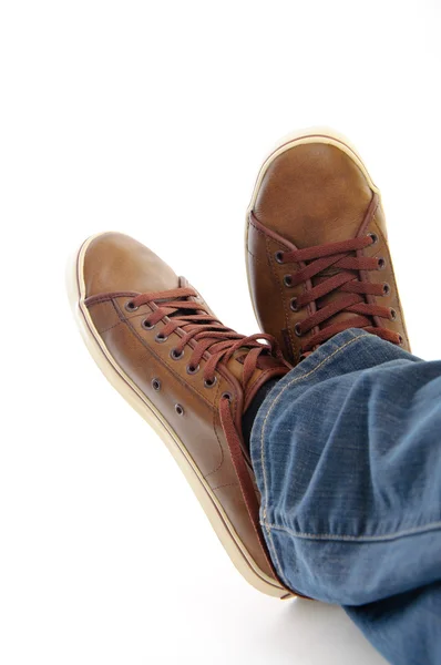 Gambe in scarpe marroni sneakers sdraiate isolate su schienale biancogr — Foto Stock