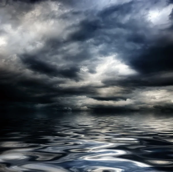 Oscuro cielo nublado y tormentoso con nubes y olas en el mar —  Fotos de Stock