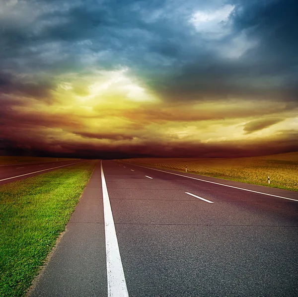 Strada asfaltata nel campo sopra il cielo tempestoso — Foto Stock