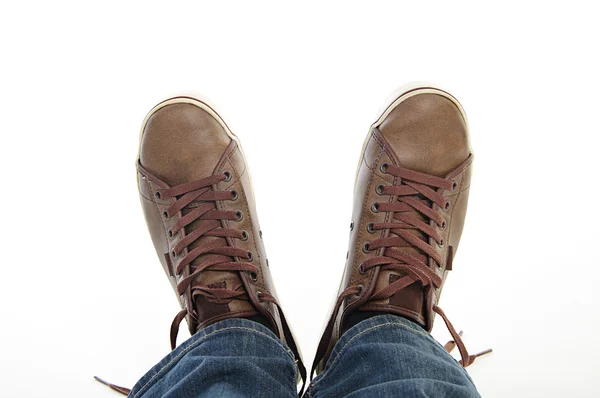 Gambe in scarpe marroni sneakers e jeans sdraiati — Foto Stock