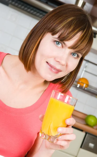 Young woman drinking orange juice at home — Stock Photo, Image