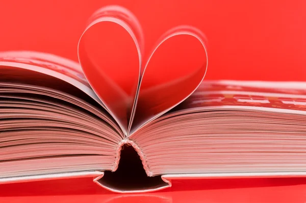 Pagine di un libro curvo a forma di cuore su rosso — Foto Stock