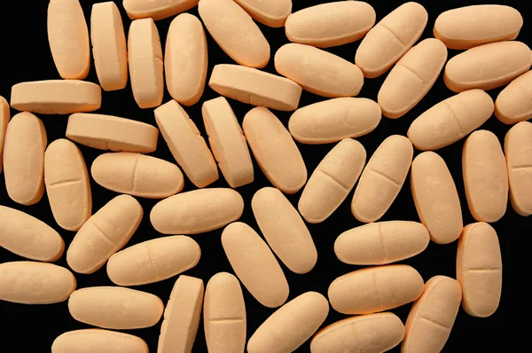 Orange pills over black macro shot — Stock Photo, Image