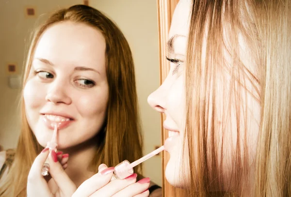 Junge Frau trägt Lippenstift vor Spiegel auf — Stockfoto