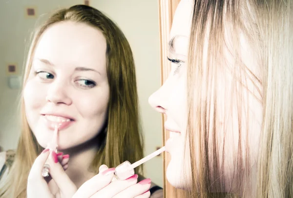 Young woman applying lipstick in front of mirror — Stock Photo, Image