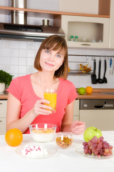 Mujer joven bebiendo jugo de naranja con muselina de cereal en casa —  Fotos de Stock